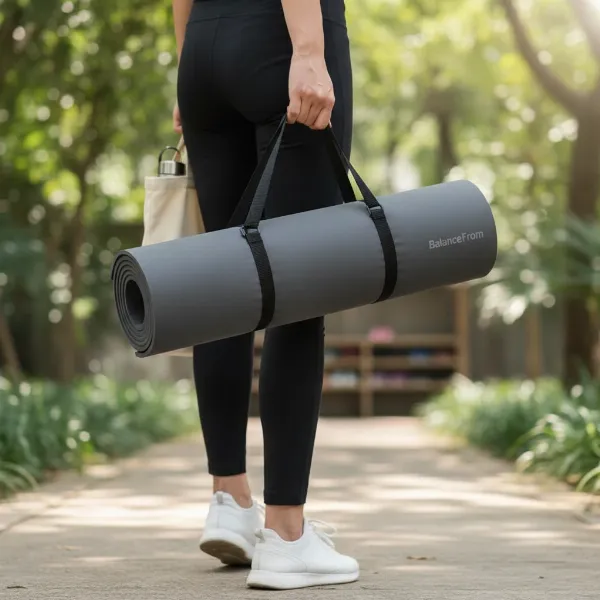 A person holding a rolled-up BalanceFrom GoYoga mat with a carrying strap, ready for transport.